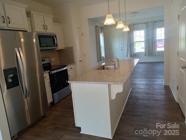 kitchen with backsplash, stainless steel appliances, sink, white cabinetry, and an island with sink