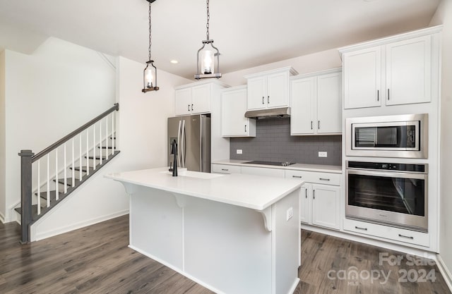 kitchen featuring white cabinets, stainless steel appliances, hanging light fixtures, and dark hardwood / wood-style floors