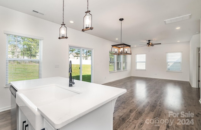 kitchen featuring a kitchen island with sink, dark wood-type flooring, pendant lighting, stainless steel dishwasher, and ceiling fan