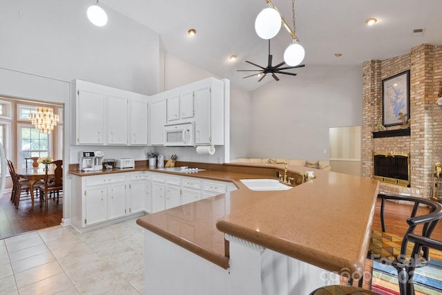 kitchen with kitchen peninsula, sink, a kitchen bar, and high vaulted ceiling