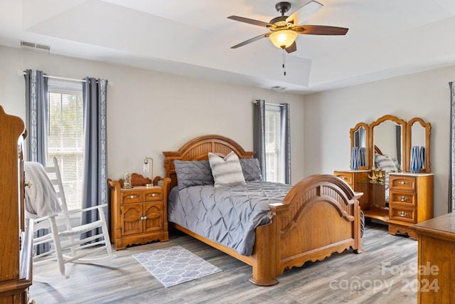 bedroom with a raised ceiling, hardwood / wood-style floors, and ceiling fan