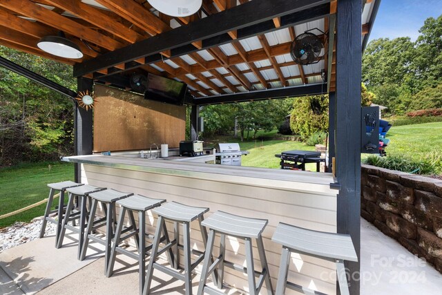 view of patio with exterior bar and a grill