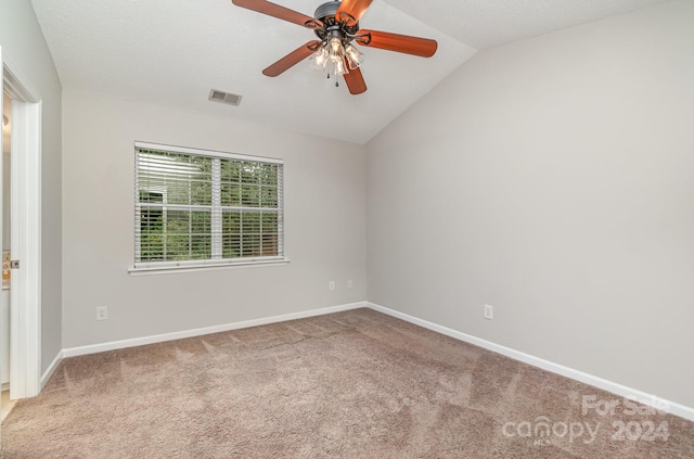 carpeted spare room featuring vaulted ceiling and ceiling fan