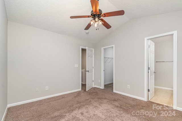 unfurnished bedroom with ceiling fan, light carpet, a spacious closet, a closet, and lofted ceiling