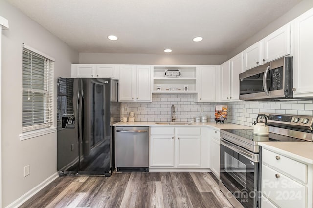 kitchen featuring sink, white cabinetry, appliances with stainless steel finishes, dark hardwood / wood-style flooring, and decorative backsplash