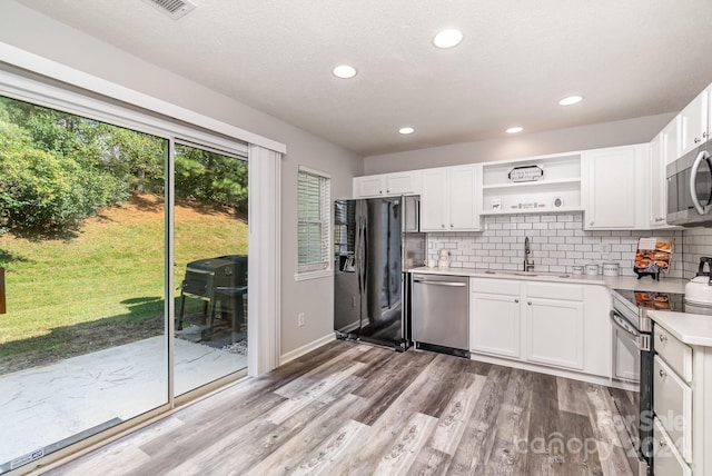 kitchen featuring white cabinets, sink, backsplash, appliances with stainless steel finishes, and light hardwood / wood-style floors