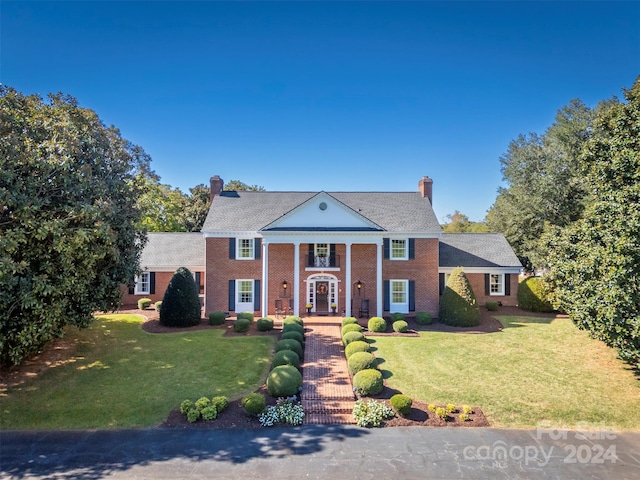 neoclassical / greek revival house featuring french doors and a front lawn