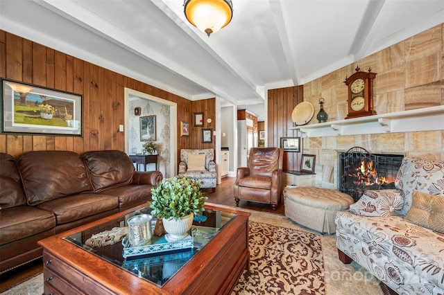 living room with beam ceiling, wooden walls, and a tile fireplace