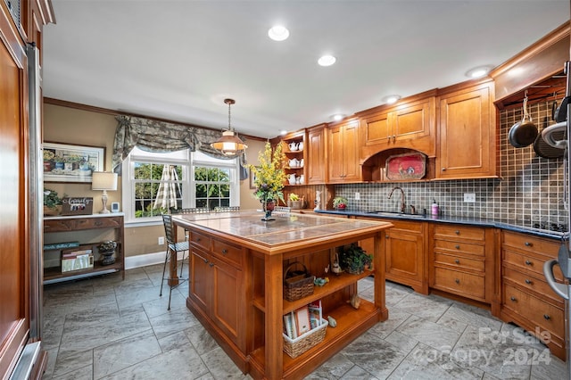 kitchen featuring sink, a center island, hanging light fixtures, crown molding, and decorative backsplash