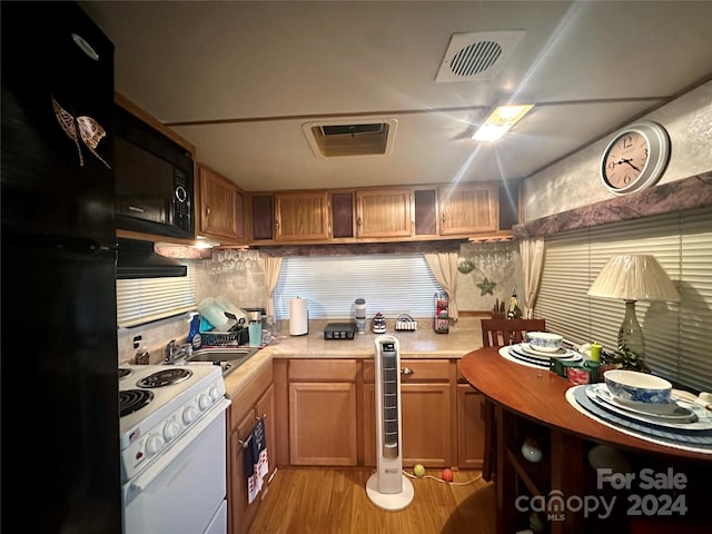 kitchen with sink, tasteful backsplash, beverage cooler, black appliances, and light hardwood / wood-style floors