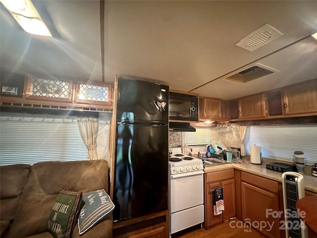 kitchen featuring custom range hood, tasteful backsplash, dark hardwood / wood-style flooring, black appliances, and sink