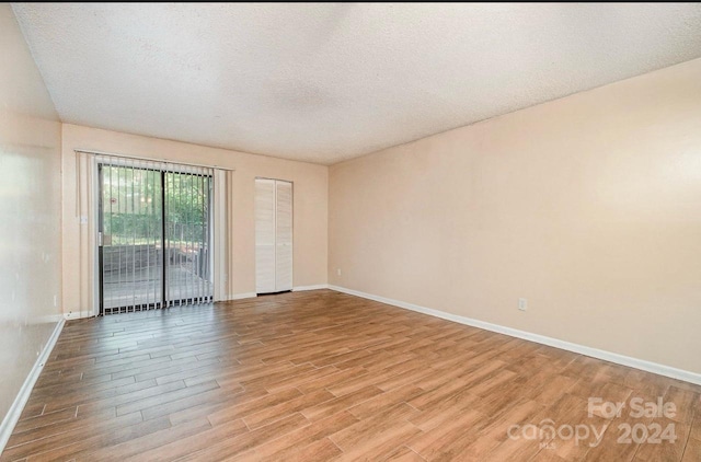 spare room with a textured ceiling and light wood-type flooring