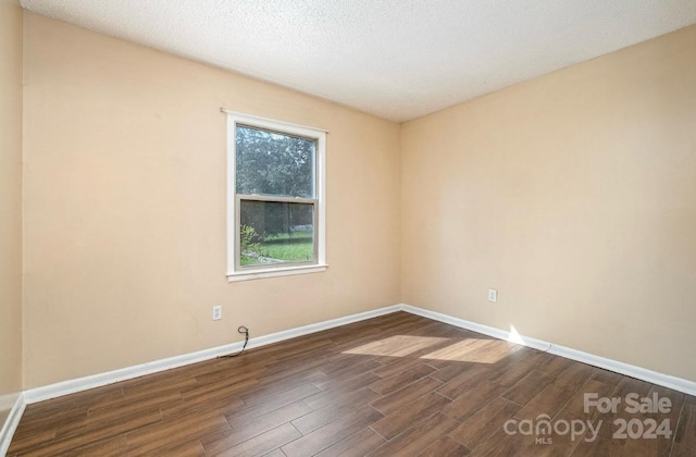 spare room with a textured ceiling and dark hardwood / wood-style flooring