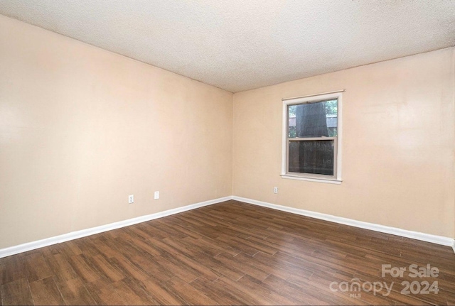 unfurnished room with a textured ceiling and dark hardwood / wood-style floors