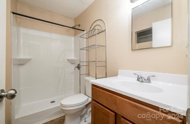 bathroom featuring a textured ceiling, a shower, vanity, and toilet