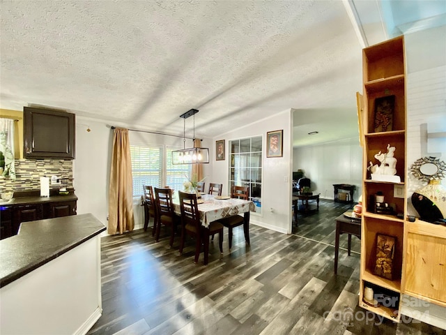 dining space with a textured ceiling, lofted ceiling, dark hardwood / wood-style floors, and a notable chandelier