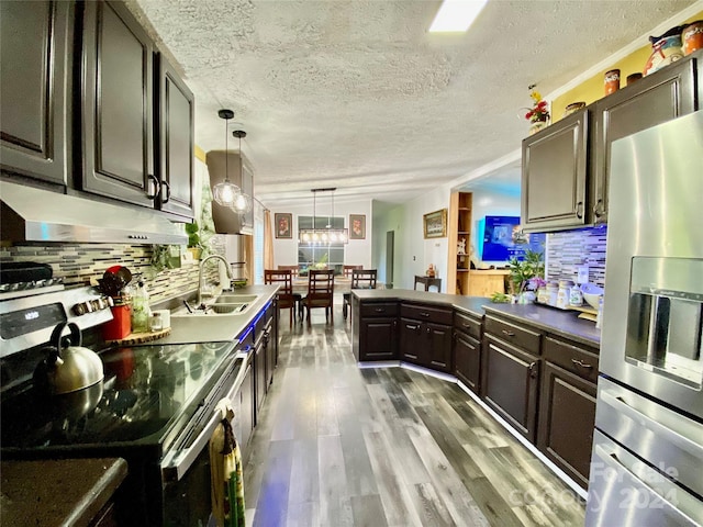 kitchen with stainless steel appliances, decorative light fixtures, hardwood / wood-style flooring, dark brown cabinetry, and sink