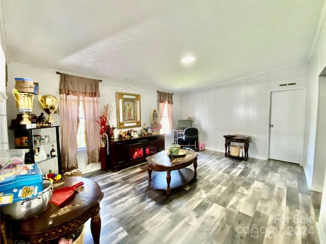 living area with ornamental molding and hardwood / wood-style floors