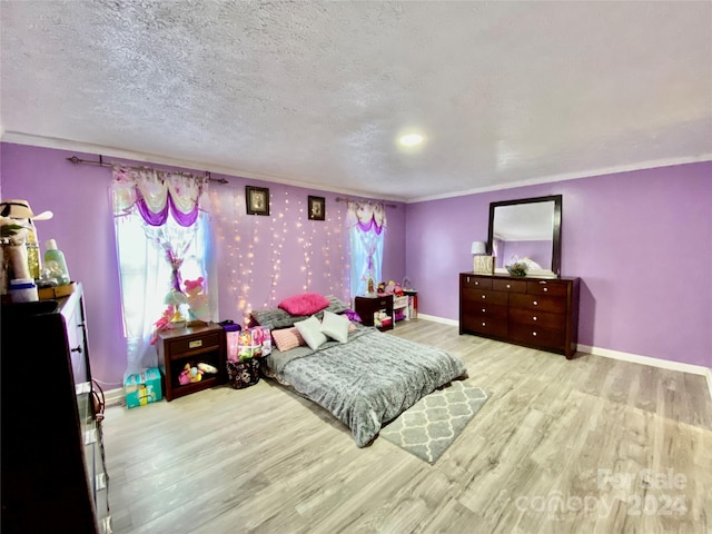 bedroom featuring a textured ceiling, light hardwood / wood-style flooring, and crown molding