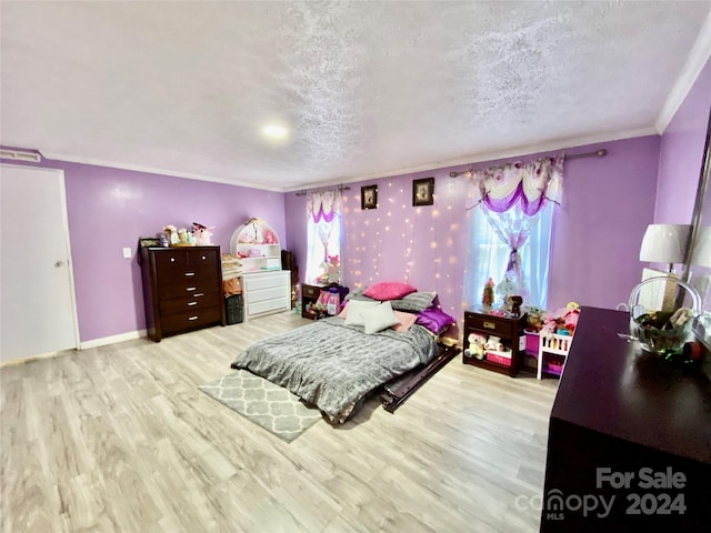 bedroom featuring light wood-type flooring, a textured ceiling, and crown molding