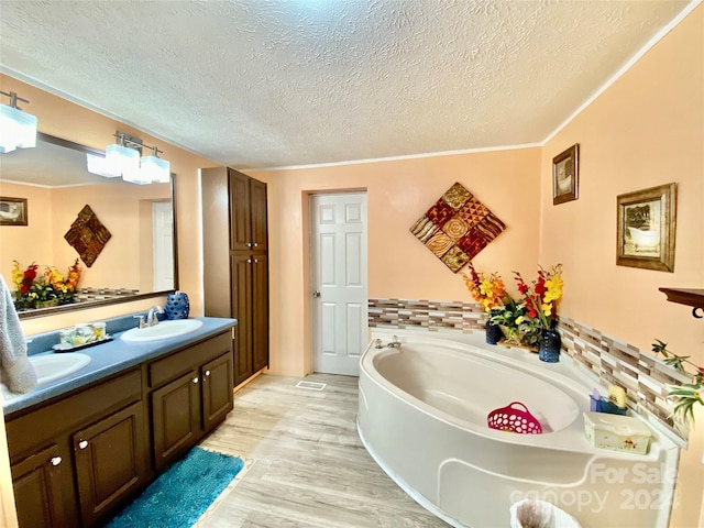 bathroom with wood-type flooring, a tub, vanity, and a textured ceiling