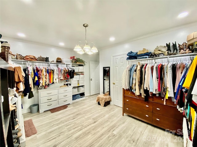 walk in closet with light hardwood / wood-style flooring and a chandelier