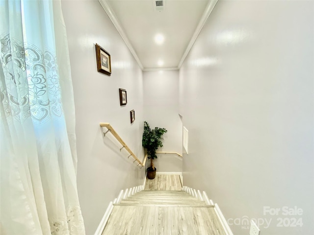 stairs featuring crown molding and hardwood / wood-style floors