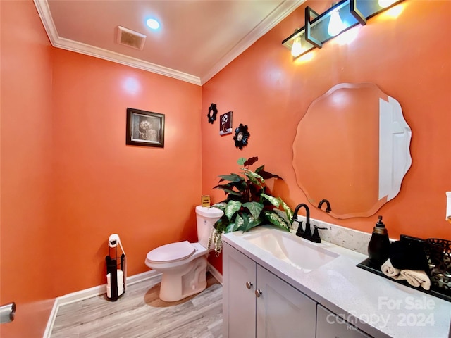 bathroom with wood-type flooring, ornamental molding, vanity, and toilet