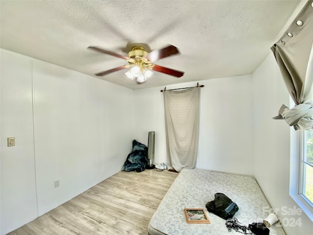 unfurnished bedroom featuring ceiling fan, a textured ceiling, and light hardwood / wood-style floors