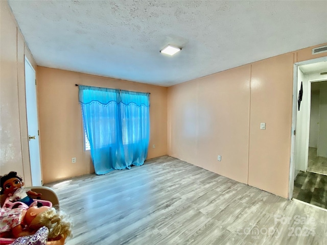 unfurnished room featuring a textured ceiling and light hardwood / wood-style floors