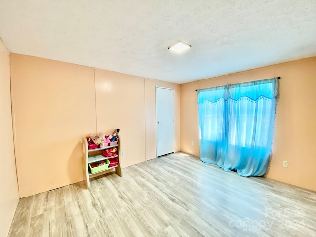 game room featuring light hardwood / wood-style floors and a textured ceiling