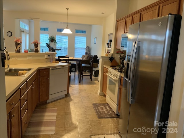 kitchen featuring sink, appliances with stainless steel finishes, hanging light fixtures, and light tile patterned flooring