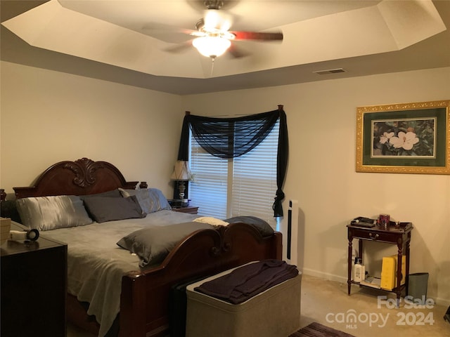 bedroom with carpet, a tray ceiling, and ceiling fan