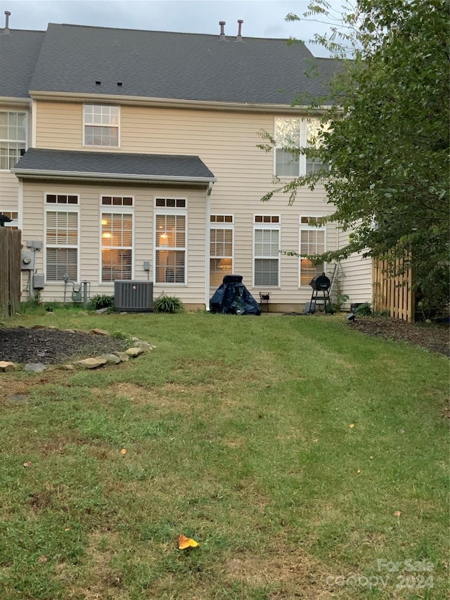 rear view of house with central AC and a yard