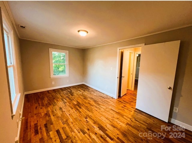 empty room with light wood-type flooring and crown molding