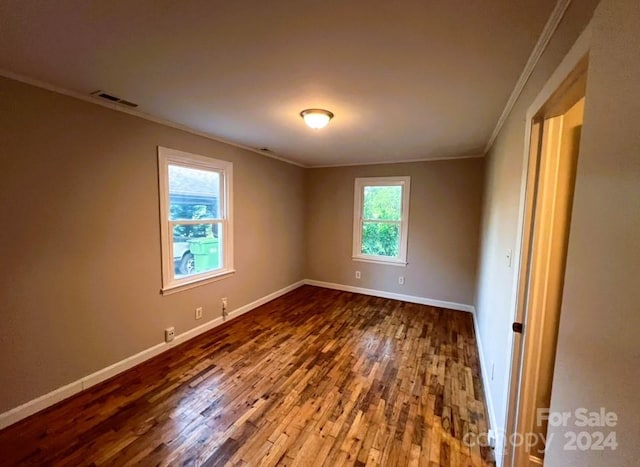 spare room with hardwood / wood-style flooring, plenty of natural light, and crown molding