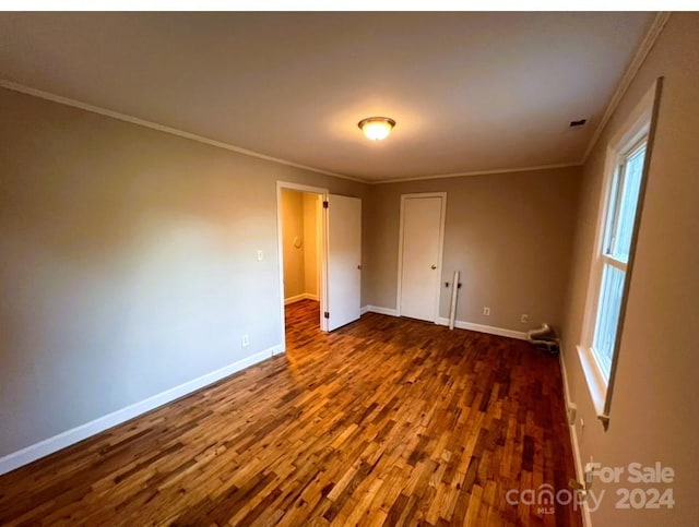 spare room with dark wood-type flooring and crown molding