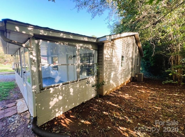 view of home's exterior featuring a sunroom and central AC