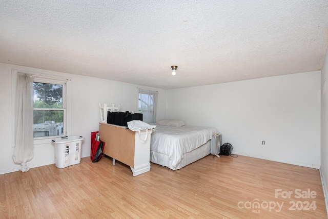 bedroom with light hardwood / wood-style flooring and a textured ceiling