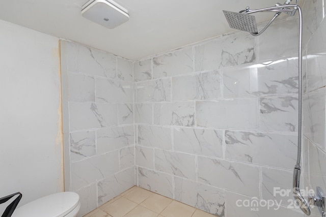 bathroom with a tile shower, toilet, and tile patterned floors