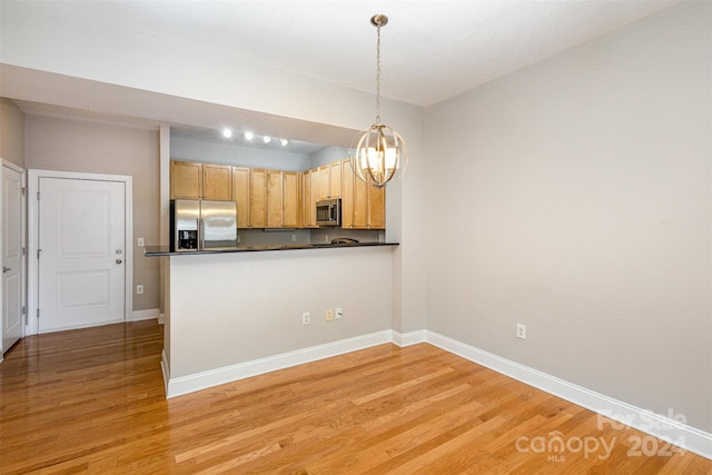 kitchen featuring kitchen peninsula, light brown cabinets, stainless steel appliances, light hardwood / wood-style flooring, and decorative light fixtures