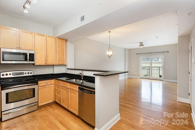 kitchen with light hardwood / wood-style floors, sink, kitchen peninsula, appliances with stainless steel finishes, and ceiling fan