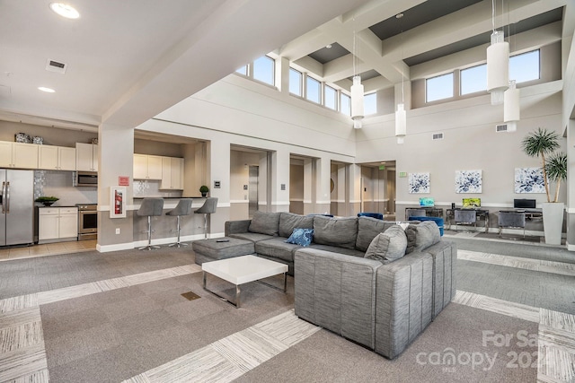 carpeted living room featuring a towering ceiling and beam ceiling