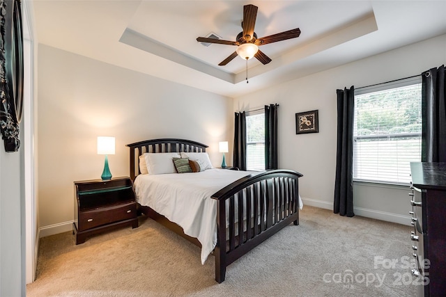 carpeted bedroom featuring a raised ceiling and ceiling fan