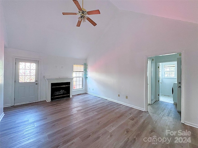 unfurnished living room with wood-type flooring, washer / dryer, ceiling fan, and high vaulted ceiling