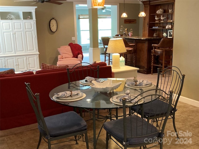 tiled dining area featuring decorative columns and ceiling fan