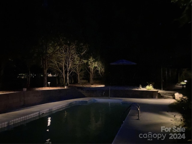 view of pool at twilight