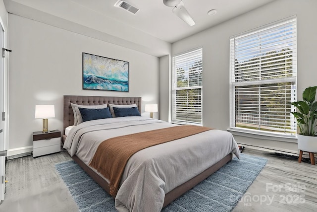 bedroom featuring multiple windows, hardwood / wood-style floors, and ceiling fan