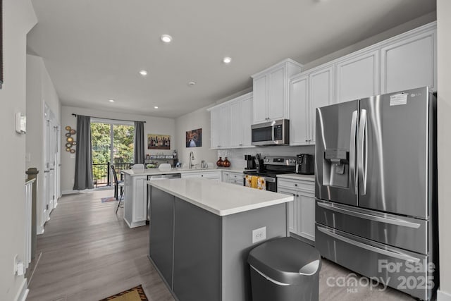 kitchen with white cabinetry, sink, stainless steel appliances, kitchen peninsula, and a kitchen island