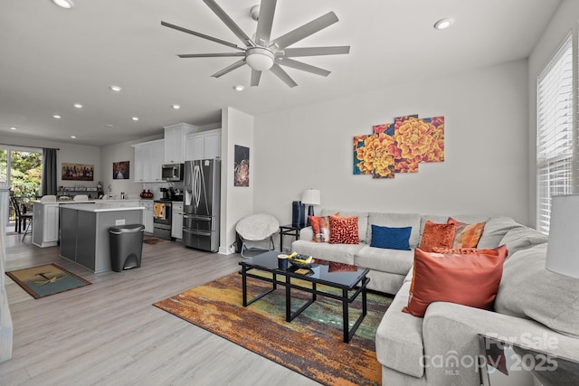 living room with ceiling fan and light hardwood / wood-style floors